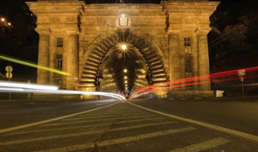 Long exposure photo of cars driving into a tunnel in budapest at night, creating streaks of light