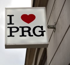 White square sign with i love prg written on it, hanging on a building facade, expressing affection
