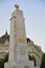 Soviet war memorial with golden star and hammer and sickle emblem standing tall against clear sky