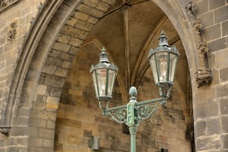 Ornate gas lamp stands beneath a stone arch, showcasing the city's rich history and craftsmanship