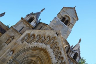 Low angle view of jaki chapel facade showing stone statues of saints and bell tower in budapest,