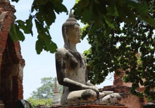 Serene buddha statue sits in peaceful meditation amidst crumbling temple ruins, showcasing