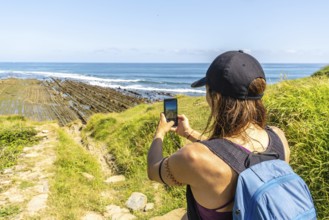 Hiker taking pictures of the impressive flysch cliffs at sakoneta beach in zumaia, basque country,