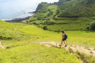 Female hiker walking down a path in the hills near sakoneta beach in zumaia, basque country, spain,