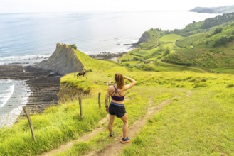 Female athlete enjoying the view of the sakoneta beach and its coastal flysch in zumaia, gipuzkoa