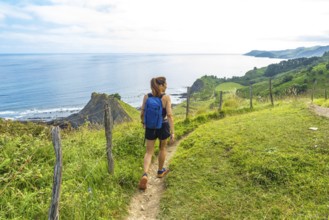 Female hiker enjoying the stunning view of sakoneta beach and its coastal flysch in zumaia, basque