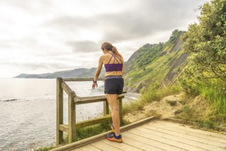 Female tourist consulting informative map at viewpoint in sakoneta beach, next to flysch in zumaia,