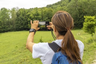 Female hiker taking pictures of the landscape with her smartphone in sakoneta beach area and its