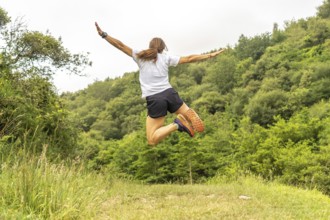 Celebrating athletic achievement, a female athlete jumps with outstretched arms in a vibrant green