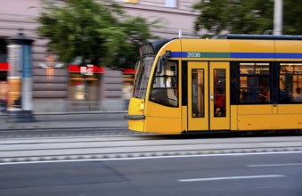 Yellow tram speeding through the bustling city center, showcasing motion blur and filled with