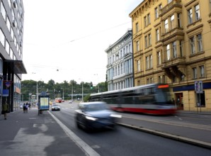 Modern tram passing fast on a street in prague with blurred car, bus stop and colorful buildings