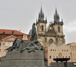 Jan hus monument standing tall in old town square, with the iconic tyn church rising majestically