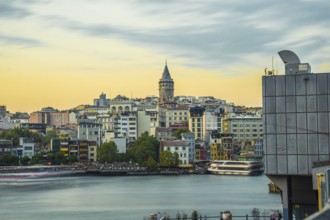 Galata tower rising above colorful buildings along the golden horn in istanbul, turkey, during a