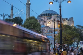 Tram gliding past the iconic hagia sophia in sultanahmet square during the enchanting blue hour in