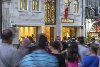 People walking on the street in front of a busy restaurant in istanbul, turkey, in motion blur