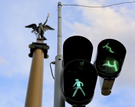 Green traffic light allows pedestrians to cross the street in budapest, hungary, with a statue