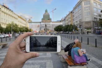 Hand holding smartphone taking photo of wenceslas square in prague, czech republic, with tourists