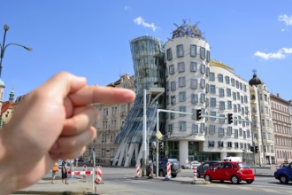 Hand pointing at the famous dancing house in prague, czech republic, a deconstructivist office