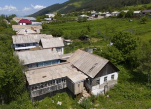 Rustic building ensemble in a rural setting surrounded by nature and green hills, aerial view,