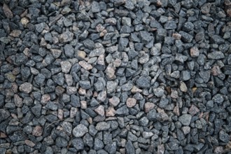 A close-up view of dark gravel featuring small, irregularly shaped stones in shades of gray and