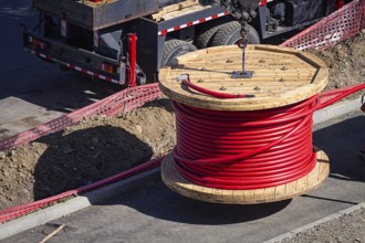 Big red cable coil, rises for installation at the city construction site, no people