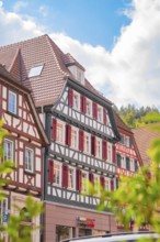 Historic half-timbered house with red shutters under a blue sky, small town of Perle Calw, Black