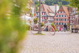Pink bicycle with flowers in the foreground of a picturesque half-timbered old town with cobbled
