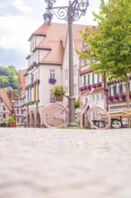 A pink bicycle in front of picturesque half-timbered houses on a sunny square, small town of Perle