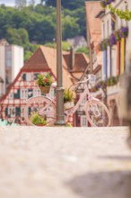 Pink bicycle leaning against a street lamp in a charming old town with red half-timbered houses,