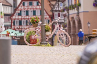 Pink bicycle with flowers next to half-timbered houses, an invitation to linger in pleasant