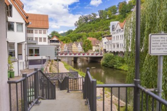 View of a river with a bridge and surrounding urban architecture in summer, small town of Perle