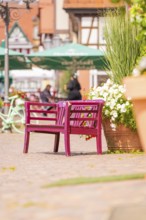 Pink bench with flowers in lively old town with cafés and summery atmosphere, small town pearl
