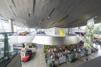 Modern building with seating areas, many plants and exhibited cars, BMW Welt, Munich, Germany