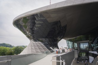 Futuristic building with reflective glass façade, leading visitors up a ramp, BMW Welt, Munich,
