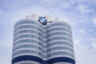 High-rise building with round glass facades and prominent logo against a slightly cloudy sky, BMW