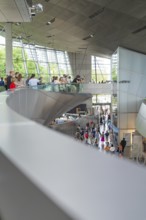 Modern interior with people moving in a wide, structured environment, BMW Welt, Munich, Germany
