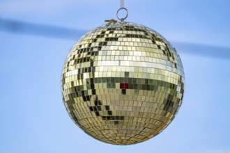 Golden disco ball, small mirrors, distributed like a mosaic, reflect light and create lighting
