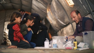 A doctor examining a displaced Syrian child inside a mobile clinic at a refugee camp. Aleppo, Syria