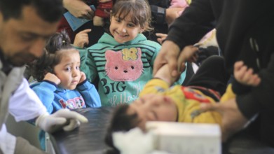 A doctor examining a displaced Syrian child inside a mobile clinic at a refugee camp. Aleppo, Syria