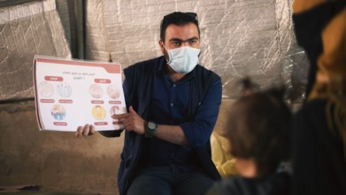A community health worker giving instructions to refugees on how to deal with the cholera outbreak