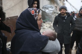A frightened mother carries her infant after he was pulled from the rubble of a deadly earthquake