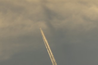 Jet passenger aircraft with a vapour trail or contrail flying in a blue sky, England, United