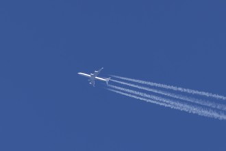 Airbus A340-300 jet aircraft of Lufthansa airlines in flight in a blue sky with vapour trails or