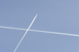 Jet passenger aircraft with a vapour trail or contrail flying crossing another contrail making a