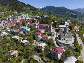 Small town with colourful houses and church, surrounded by green mountains under a clear sky,