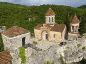 Historic church with tiled roofs on a hill surrounded by dense forest, aerial view, Motsameta