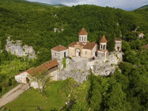Historic monastery on steep hills surrounded by lush greenery, aerial view, Motsameta Monastery,