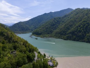 Panoramic view of a green river in a mountainous landscape with a boat, aerial view, confluence of