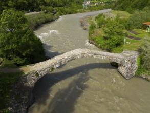 Aerial view of an old stone bridge spanning a river surrounded by green nature, aerial view, stone