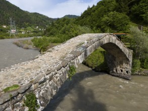 Old stone bridge over a river, embedded in a wooded landscape, aerial view, stone arch bridge